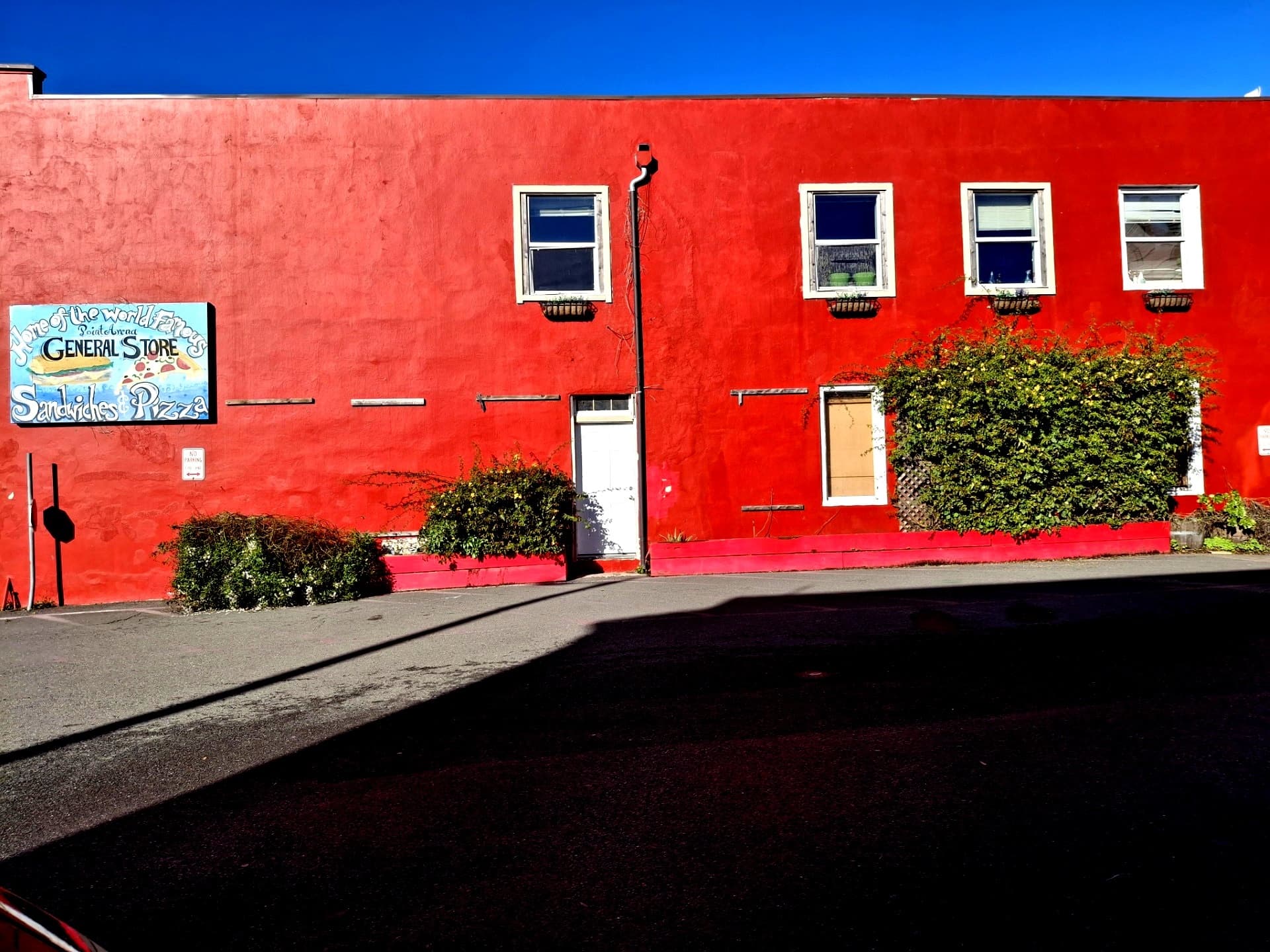 The red-painted Point Arena General Store storefront under a clear blue sky