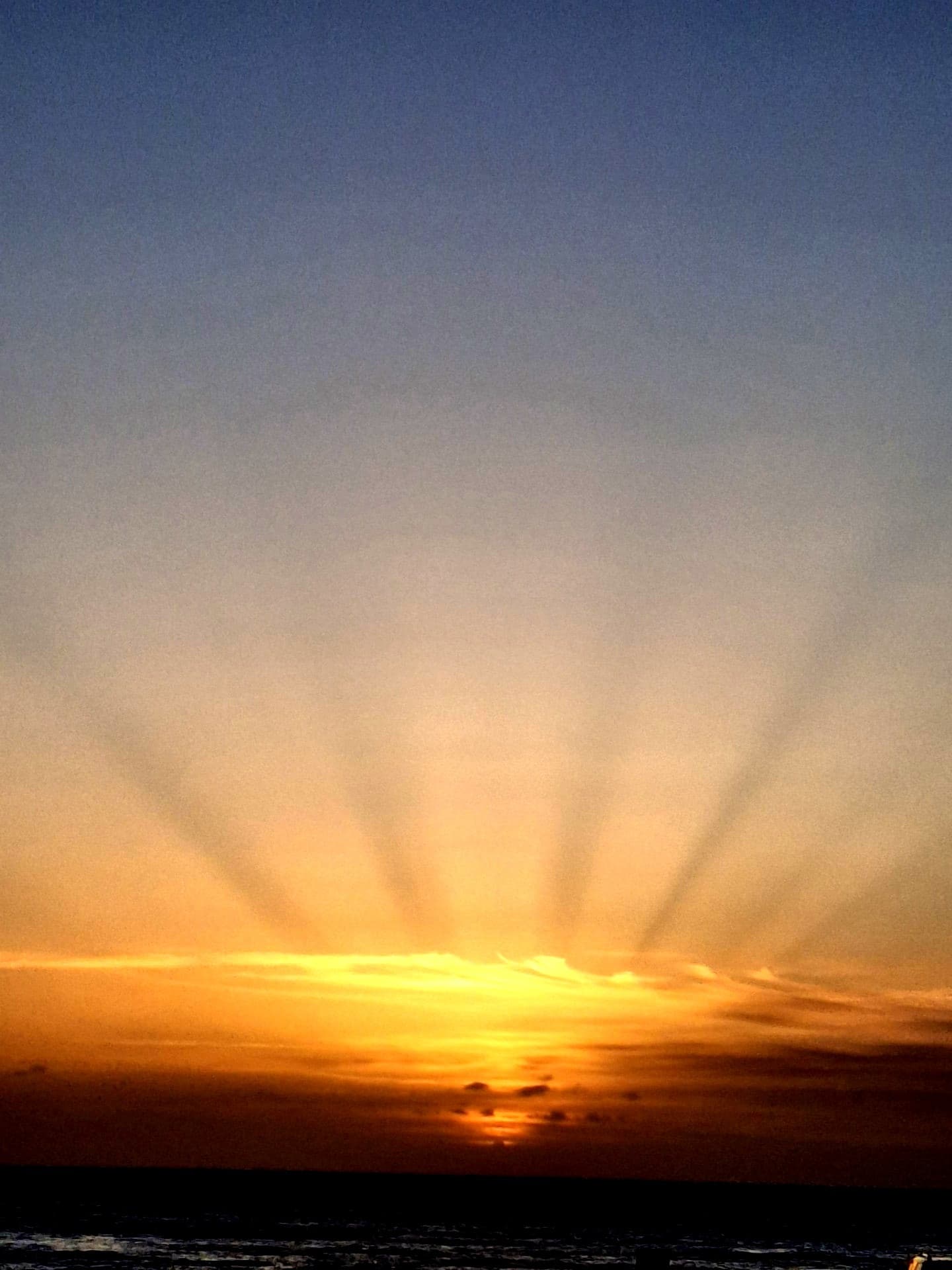 Sunbeams breaking through clouds over the ocean at sunset